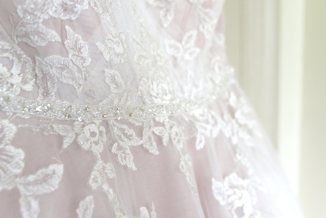 detail of a wedding dress of flowery white fabric over pink fabric by handfasting photographer uk and EU Nadina Bee
