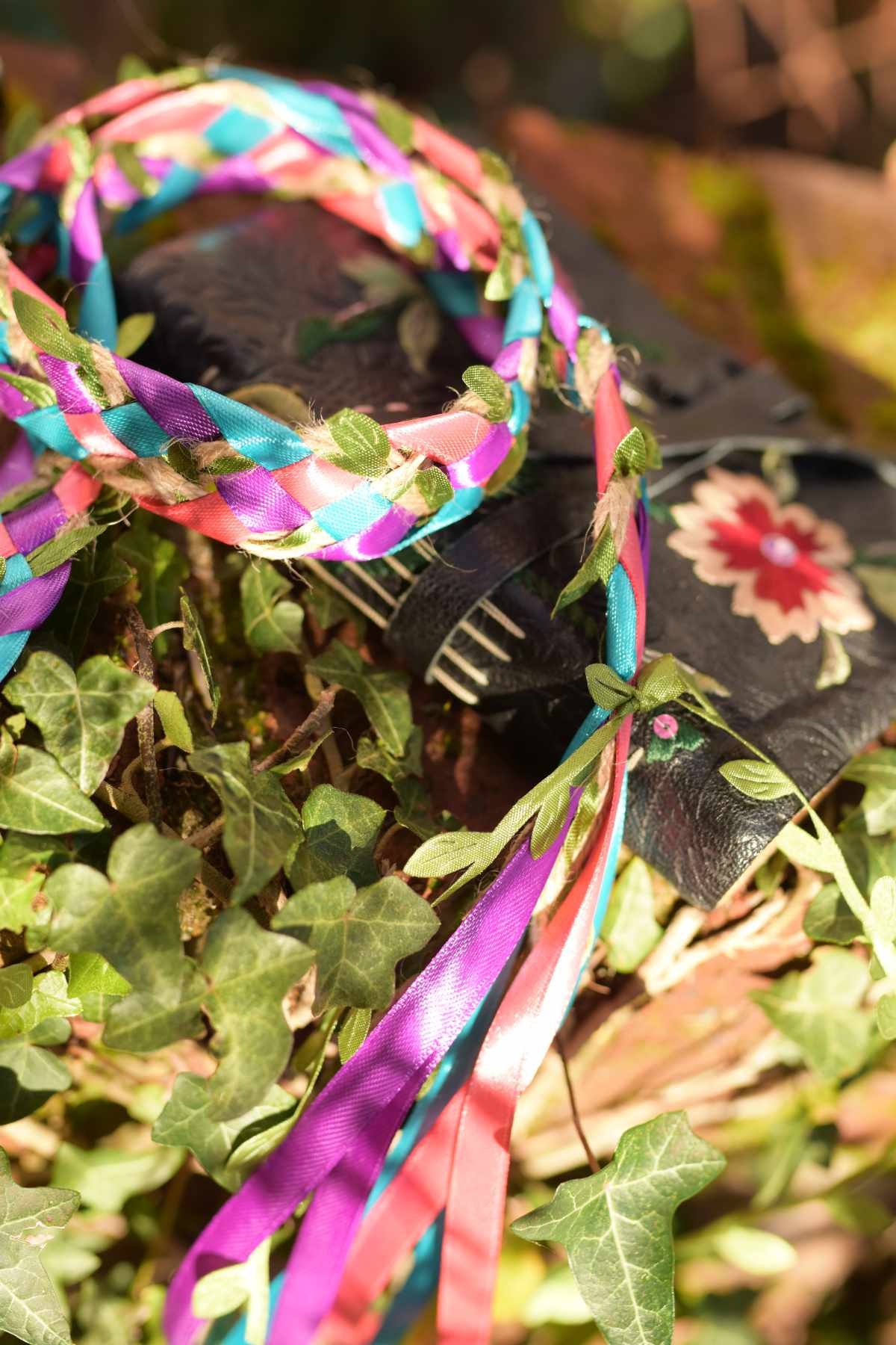 Photo by specialist handfasting photographer Nadina Bee of a grimoire and multicoloured handfasting cord on a bed of ivy