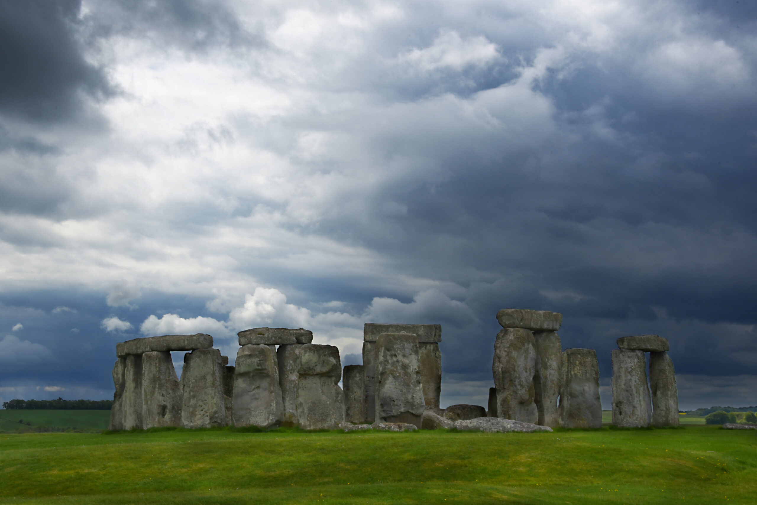 Logo elements ARROWS copyright Nadina Bee Perfect wedding photos in the UK at Stonehenge Handfasting Venue in unpredictable weather. Dramatic dark clouds have gathered over Stonehenge with the sun managing to break through.