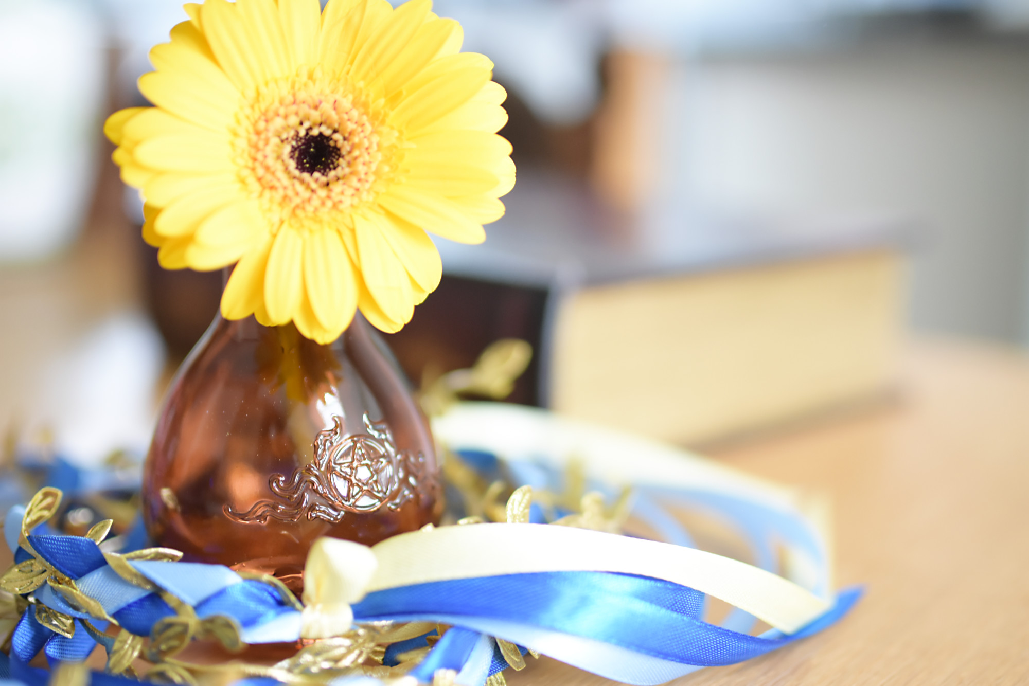 blue and beige handfasting ribbon with a yellow flower in a brown glass vase with a pentagram decoration for blog: should you hire a celebrant for your handfasting ceremony
