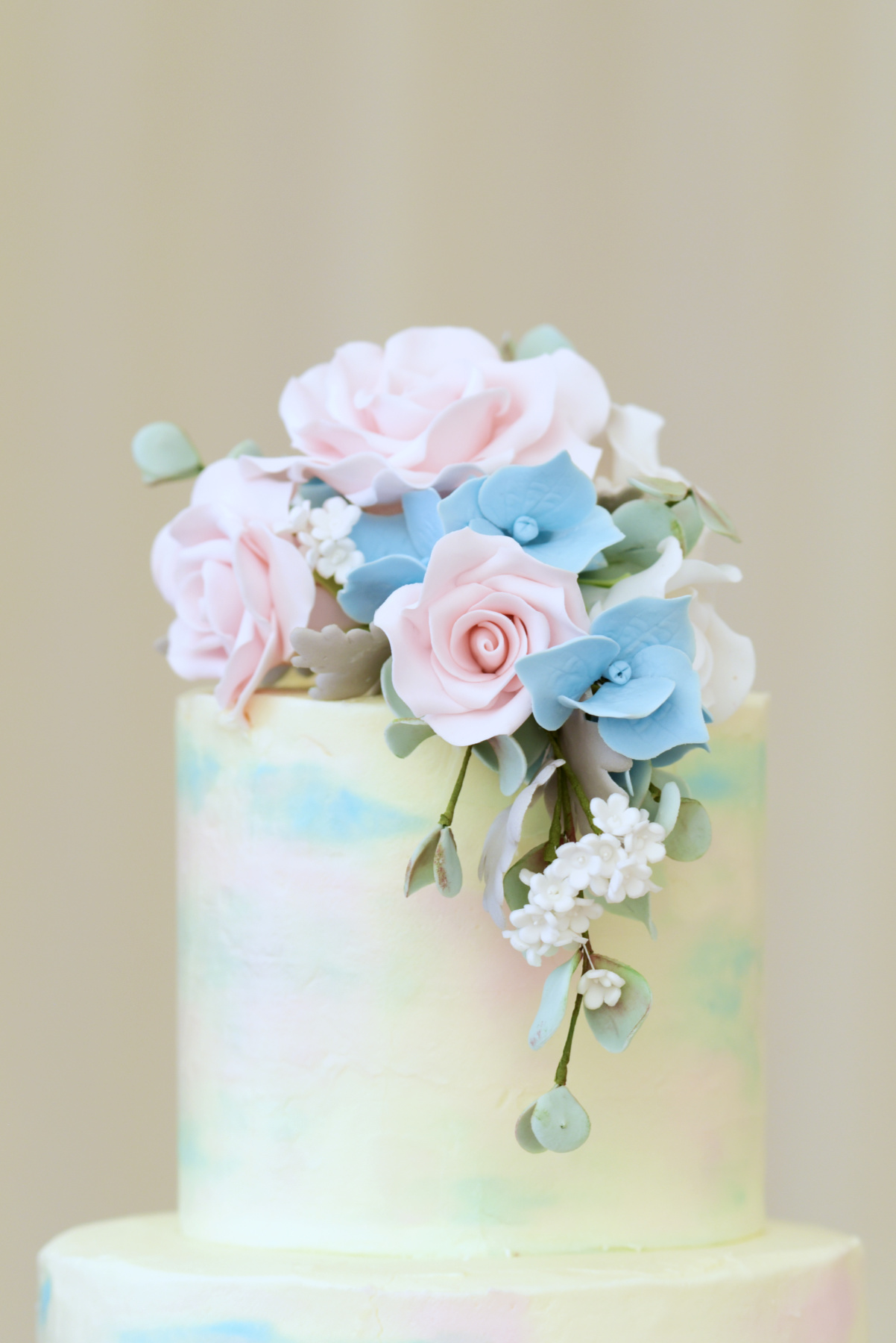 Delicate Wedding Cake in pastel colours with pink and baby blue sugar flowers at the Mill House Reading Wedding Photographer Nadina Bee
